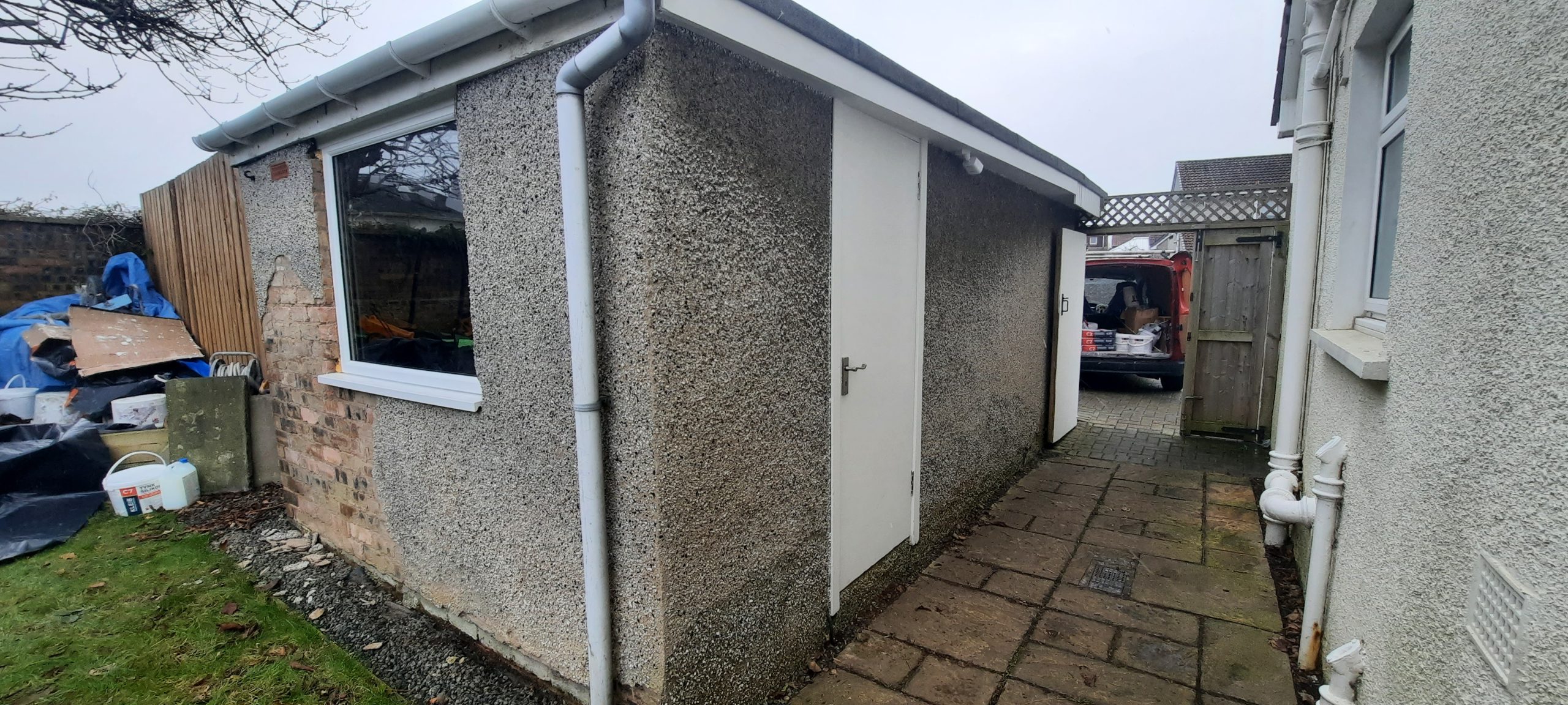 roughcast render repair along garage pathway