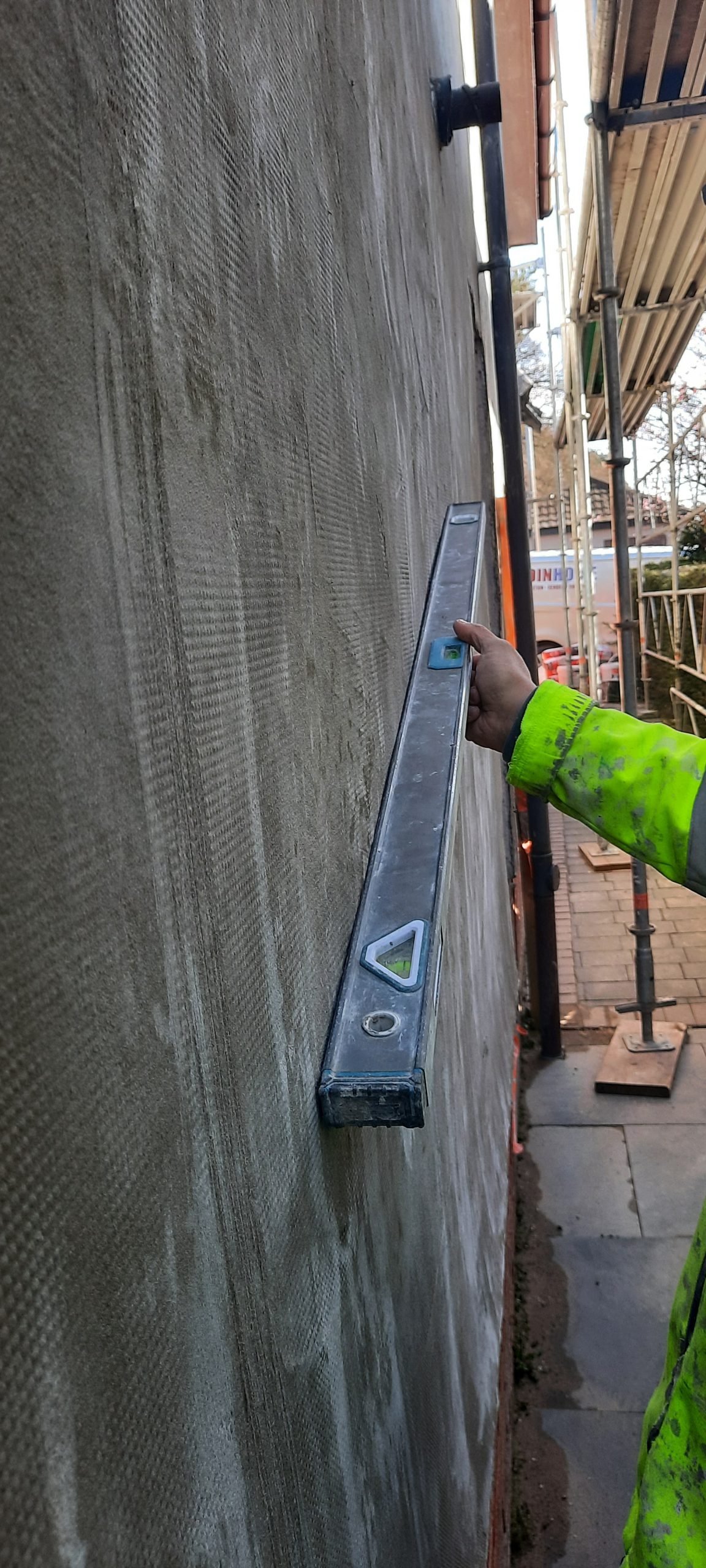 roughcast render repair on side wall with ladder