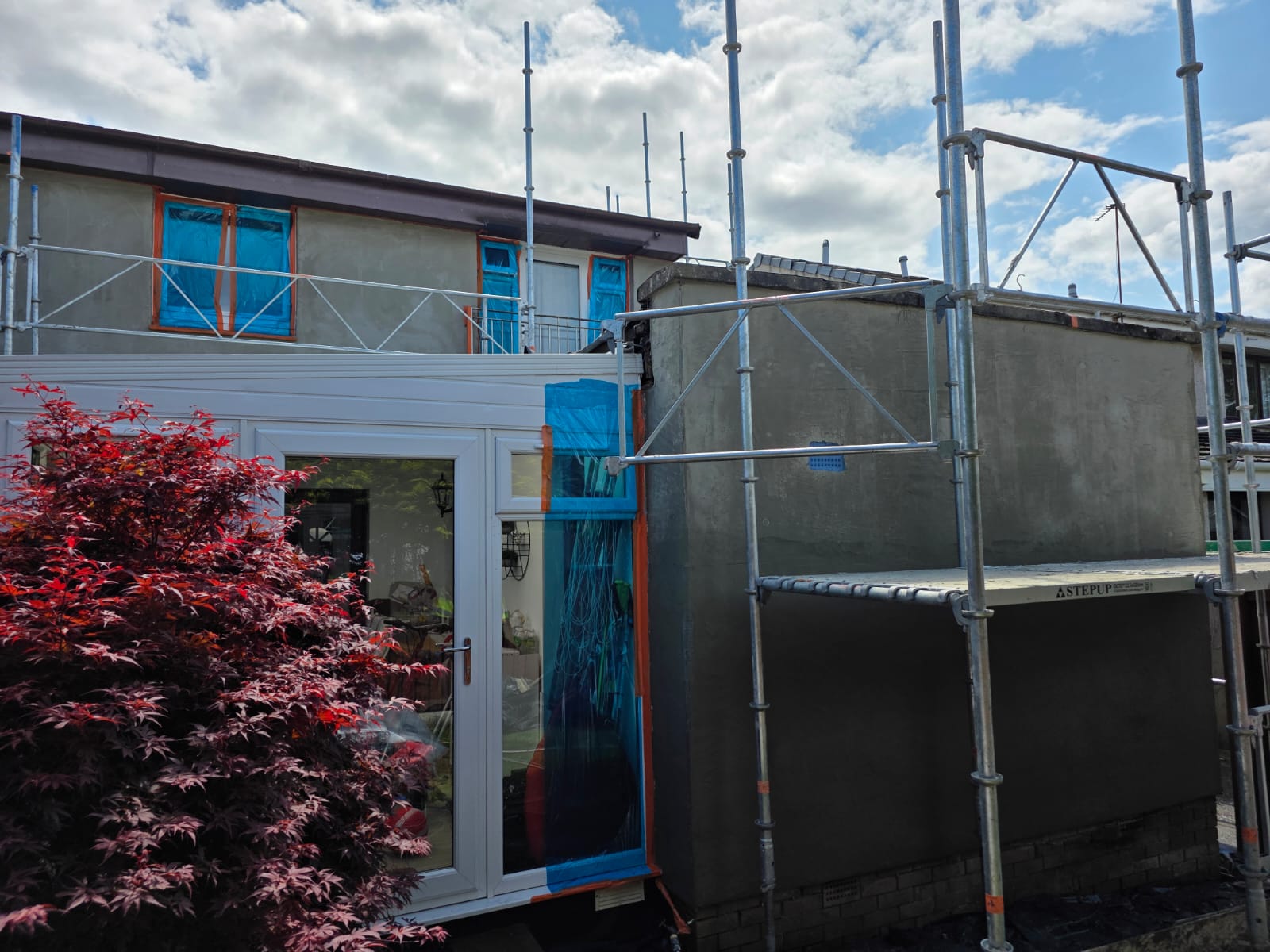 long facade undergoing roughcast render repair under scaffold