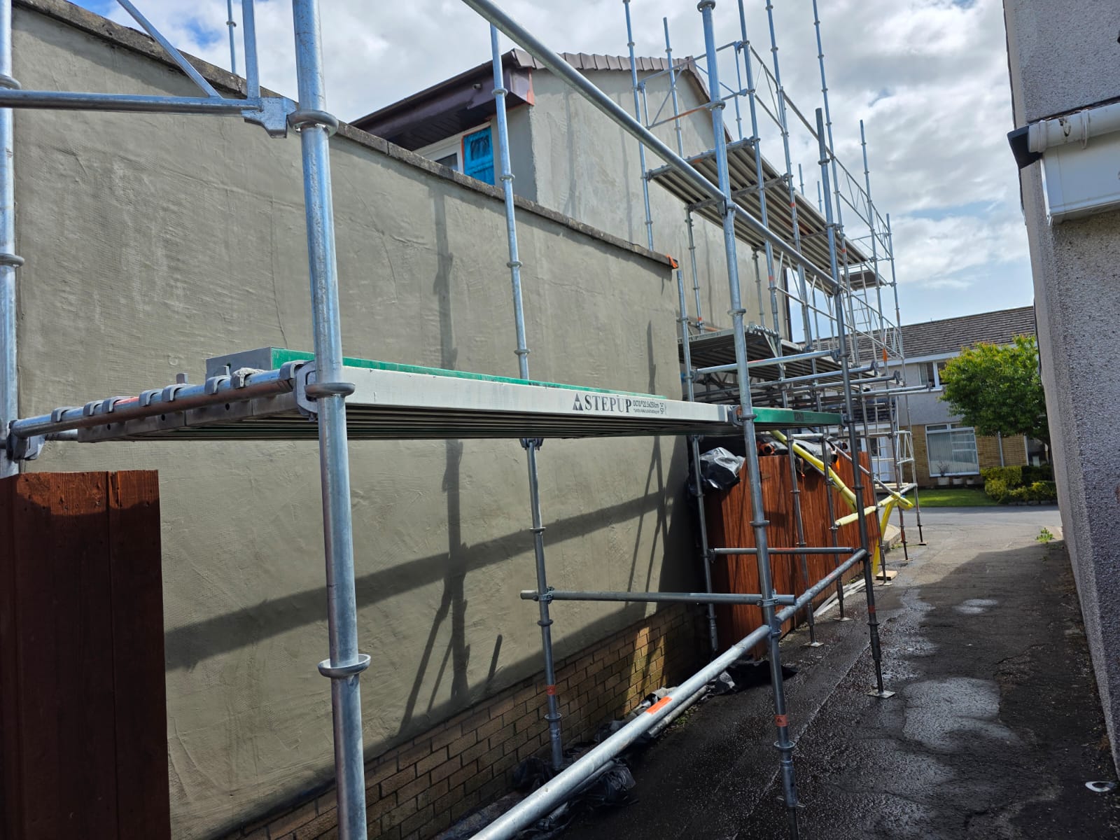roughcaster Edinburgh working on side wall behind conservatory roof