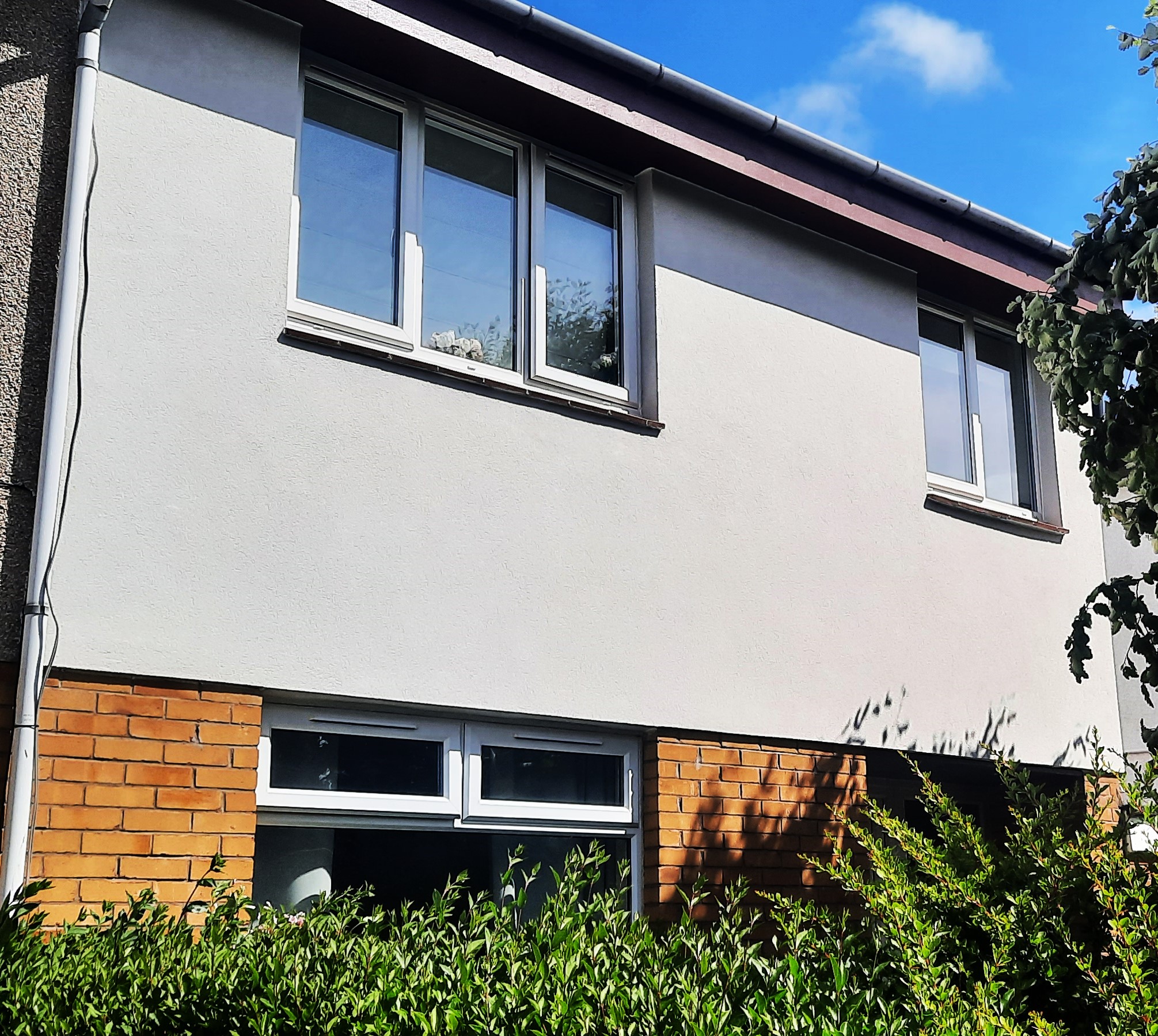 side elevation featuring freshly applied roughcast render repair over old surface